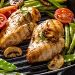 Close-up of healthy home cooked food, grilled chicken in a skillet with green vegetable, mushrooms and tomatoes